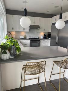 a kitchen with white cabinets and a counter with two chairs at Mountain Serenity Meets Luxury in Squamish