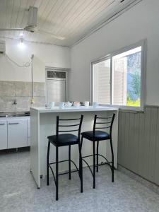 a kitchen with two black chairs at a counter at DEPARTAMENTOS A METROS DE LA UNAF in Formosa