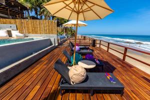 a deck with chairs and an umbrella and the beach at Casa Colibrí in Máncora