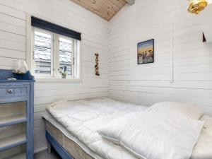 uma cama num quarto com paredes brancas e uma janela em Holiday home Karrebæksminde XLIV em Karrebæksminde