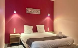 ein Schlafzimmer mit einem großen Bett mit einer roten Wand in der Unterkunft Hôtel Les Demoiselles in Essoyes