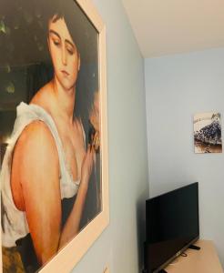 una pintura de una mujer en una pared junto a un televisor en Hôtel Les Demoiselles en Essoyes