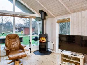 a living room with a fireplace and a chair and a television at Three-Bedroom Holiday home in Højby 1 in Højby