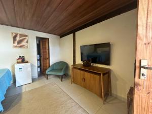 a living room with a flat screen tv and a chair at Pousada Beach House Coqueirinho in Jacumã