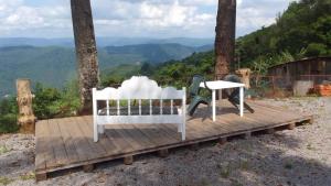 un banc blanc et une table sur une terrasse en bois dans l'établissement Encosta Dos Pinheiros, à Gramado