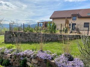 a stone retaining wall in front of a house with purple flowers at Gîte spacieux 10 pers à Vagney - Sauna, jeux, proche Gérardmer - FR-1-589-400 in Vagney