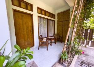 龙目岛库塔Lara Homestay的门廊配有椅子和木门
