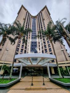 a large building with palm trees in front of it at Flat de Luxo Aeroporto Congonhas - Hotel in Sao Paulo