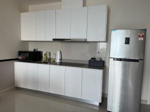 a kitchen with white cabinets and a refrigerator at Homestay KLGCC KL Golf Country Club Senada Residences in Kuala Lumpur