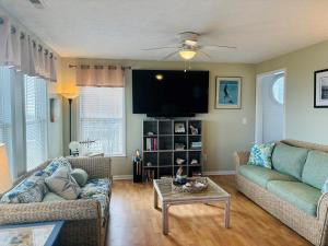 een woonkamer met 2 banken en een flatscreen-tv bij Aquarius home in Holden Beach