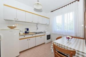eine Küche mit einem Tisch und einem weißen Kühlschrank in der Unterkunft Apartments with a parking space Zadar - 22541 in Zadar