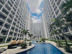 a swimming pool in front of two tall buildings at 2 Side-by-Side P00L Front Condos, 6 Beds, 2 CR, 2 Kitchen for 10 Guests at MOA in Manila