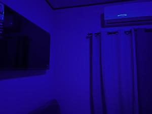 a dark room with a blue light and a television at Enjoy this Vacation Home close to the beach! in La Ceiba