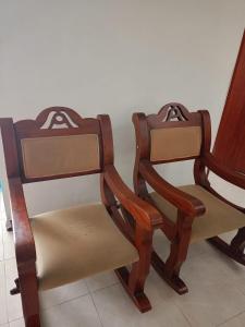 2 sedie in legno sedute accanto a un muro di HABITACION CERCA AL AEROPUERTO a Pereira
