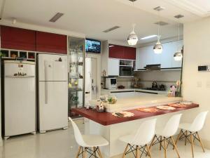 a kitchen with white appliances and a counter with white chairs at Demi-suíte privativa em casa familiar 2 in Itajaí