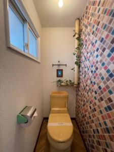 a bathroom with a toilet and a mosaic wall at シャルムイースト in Irifunechō
