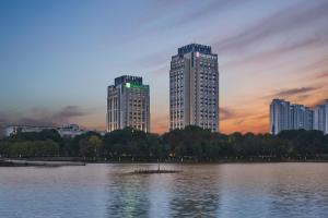 dois edifícios altos em frente a um grande lago em HUALUXE Kunshan Huaqiao, an IHG Hotel - F1 Racing Preferred Hotel em Kunshan