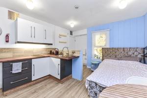 a kitchen with blue cabinets and a bed in a room at Cosy studio flat on a budget in London