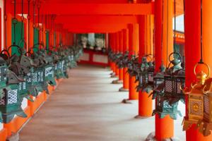 a row of orange columns with lights in a temple at Ranjatai in Nara