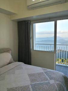 a bedroom with a bed and a large window at Blowing In The Wind in Tagaytay