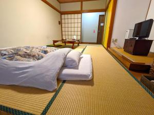 Cama grande en habitación con TV en KULABO 大正館, en Nagato