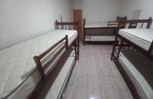three bunk beds in a room with a tile floor at Nossa Casa com Piscina in Guarapari