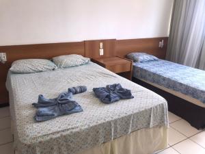 two beds in a hotel room with shoes on them at Flat Ponta Negra vista para o mar in Natal