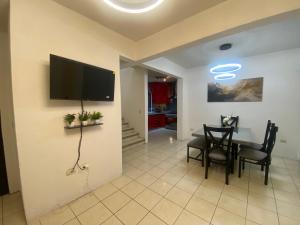 a living room with a table and a television on a wall at HERMOSA CASA PRIVADA EN FRACC VALLE VERDE, AL SUR DE LA CIUDAD. in Tapachula