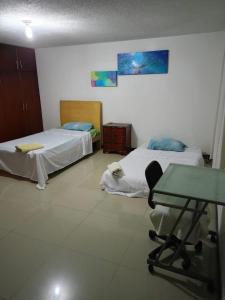 Habitación con 2 camas y mesa. en HABITACION CERCA AL AEROPUERTO, en Pereira