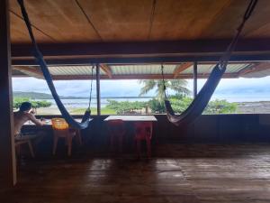 a man sitting at a table in a room with swings at Nias Shady Palm surfcamp in Lagudri