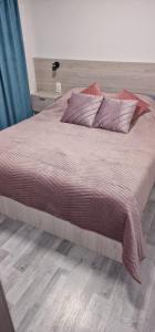ein großes Bett mit lila Laken und Kissen in der Unterkunft Angel in Kołobrzeg