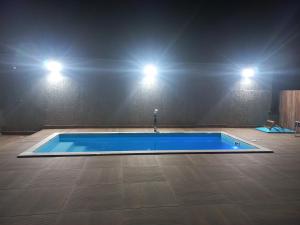 a blue swimming pool in a room with two lights at Nossa Casa com Piscina in Guarapari