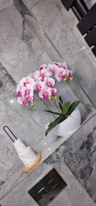 eine weiße Vase mit rosa Blumen auf dem Tisch in der Unterkunft Angel in Kołobrzeg