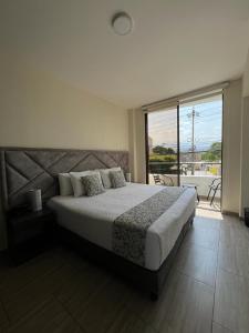 a bedroom with a large bed and a large window at HOTEL LE FALEP in Anapoima