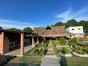 un edificio con tetto di paglia e giardino di CASA FINCA CERCANA A CTG a Turbaco