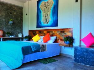 a bedroom with a blue bed with colorful pillows at Pretty Villa in Gelioya