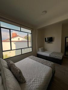 a bedroom with two beds and a large window at HOTEL LE FALEP in Anapoima