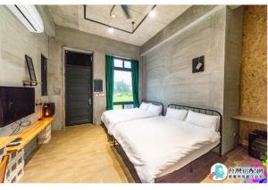 a bedroom with a bed with white sheets and a tv at 隱月民宿 in Hengchun South Gate