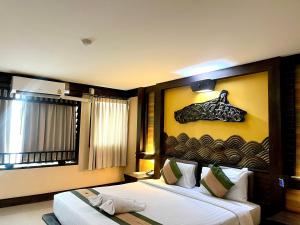 a bedroom with two beds and a painting on the wall at Ruean Phae Royal Park Hotel in Phitsanulok