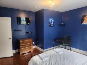 een slaapkamer met een blauwe muur, een bed en een bureau bij spacious and indulging in Meriden