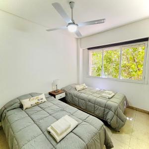 2 Betten in einem Schlafzimmer mit Deckenventilator in der Unterkunft M&S Amoblado Temporal in Neuquén