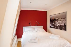 a bedroom with a red accent wall and a white bed at Perfect Perch for Legal Eagle - Winchester Law Courts, High St, Westgate Museum in Winchester