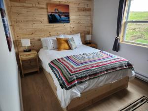 a bedroom with a bed with a wooden wall at Seaclusion Twillingate in Twillingate