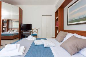 a bedroom with a large white bed and a television at Casa Mia a Roma Battistini in Rome