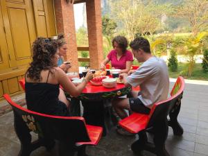 Un groupe de personnes assises autour d'une table à manger dans l'établissement Vang Vieng Romantic Place Resort, à Vang Vieng