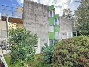 an apartment building with green windows and bushes at Studio Lamalou-les-Bains, 1 pièce, 2 personnes - FR-1-451-66 in Lamalou-les-Bains