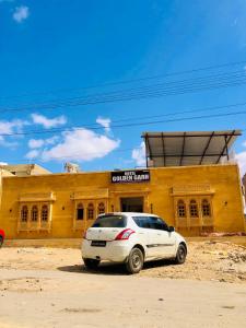 une voiture blanche garée devant un bâtiment jaune dans l'établissement Hotel Golden Garh, à Jaisalmer