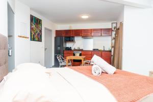 Cet appartement comprend une chambre avec un lit blanc et une cuisine. dans l'établissement Heireva Cosy & Modern Studio Perfect for Explorers and Business Travelers, à Papeete