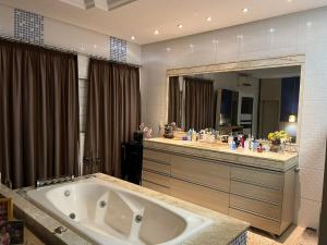 een badkamer met een groot bad en een grote spiegel bij ACONCHEGANTE (SUITE) in Rio Verde