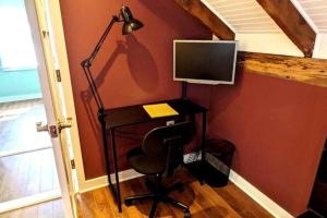 - un bureau avec un moniteur et une chaise avec une lampe dans l'établissement Walkable Elmwood Cottage, No Chores 2Bath 2BR 2Car, à Buffalo